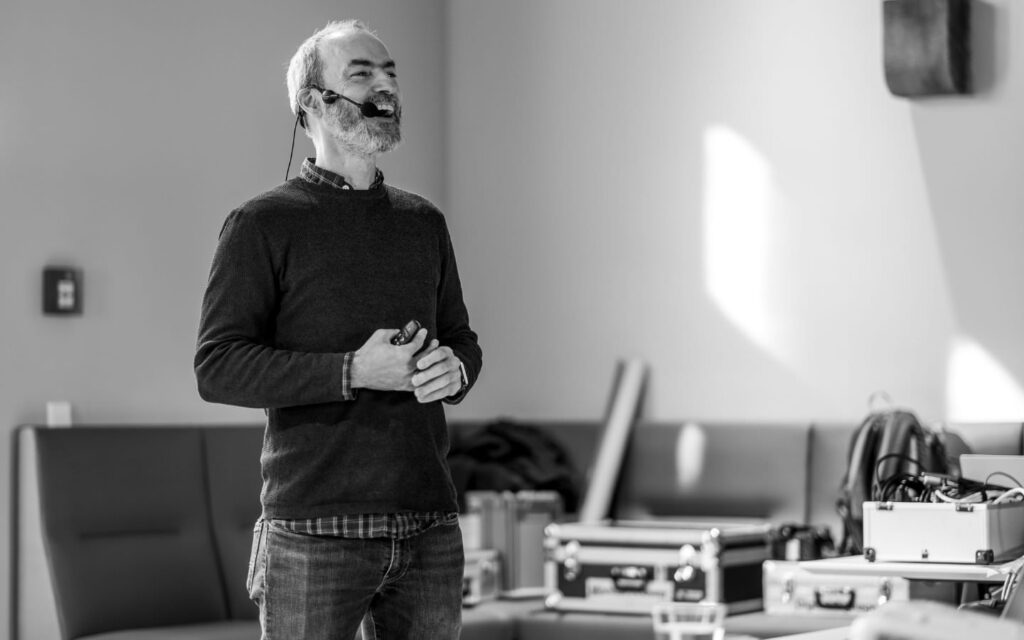 Torsten Landsiedel auf der Bühne des WordCamp Karlsruhe. Er hat ein Headset auf und lacht gerade in Richtung des Publikums.